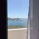 Monte Vista Lemnos Apartments offers a balcony view over the Aegean Sea, with blue water, rocky headland, and a quiet coastal shoreline.