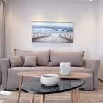 Bright Monte Vista Lemnos Apartments living area with a beige sofa, nested coffee tables, textured decor, and a framed seascape above in a modern lounge.
